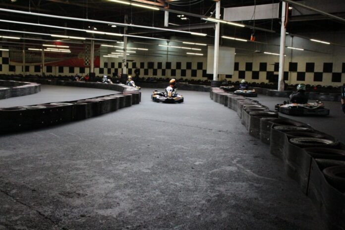 Hurricane Dolhain Karting : avec plusieurs pilotes en pleine course. Le circuit est délimité par des pneus, avec plusieurs virages et une piste assez large. L’ambiance est typique d’une session de karting, sportive et dynamique.